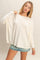 woman wearing a cream oversized long sleeve top paired with denim shorts