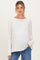 woman wearing a cream long sleeve maternity top paired with blue jeans and holding her hand in the pocket