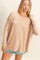 woman wearing a beige oversized long sleeve top with a relaxed fit and denim shorts