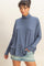 woman wearing a relaxed fit blue turtleneck top paired with a denim mini skirt
