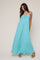 woman wearing a light blue maxi dress with a tie bow detail and spaghetti straps, standing on a neutral background