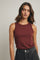 woman wearing a maroon sleeveless top with a round neckline and paired with high-waisted black jeans