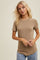woman wearing a light brown short sleeve ribbed top with a round neckline and a relaxed fit.