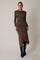 woman wearing a brown patterned long sleeve dress with a side slit and black knee-high boots