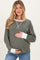 woman wearing a green striped maternity sweater with white cuffs and a baby bump visible, holding her belly