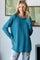 woman wearing a teal oversized knit sweater with long sleeves and a relaxed fit, paired with distressed jeans