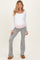 woman wearing a white long sleeve maternity top and gray flared pants, showcasing her baby bump