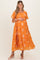 woman wearing an orange maternity dress with floral embroidery and short sleeves, holding her baby bump