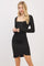 woman wearing a black long sleeve fitted dress with a square neckline and ruched side detailing