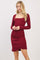woman wearing a burgundy long sleeve ribbed dress with a square neckline and ruched detail at the waist
