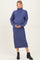 woman wearing a cozy purple maternity sweater dress with a turtleneck and holding her baby bump