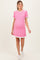 woman wearing a pink ribbed maternity dress with white ruffle details and a visible baby bump
