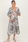 woman wearing a black and white paisley print maternity dress and cradling her baby bump