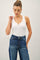 woman wearing a white ribbed tank top and high-waisted blue denim jeans