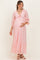 woman wearing a pink lace maternity maxi dress with three-quarter sleeves and a tie detail, holding her baby bump
