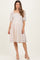 woman wearing a light pink maternity dress with puff sleeves and a square neckline, showing her baby bump