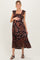 woman wearing a black floral maternity maxi dress with ruffled sleeves and a side slit, holding her baby bump