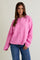 woman wearing a bright pink button-up oversized sweater with long sleeves and a relaxed fit, paired with blue jeans