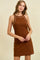 woman wearing a brown sleeveless mini dress with white detailing around the neckline