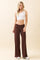 woman wearing a white cropped tank top and brown wide-leg pants with a fitted waistband