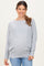 woman wearing a light gray long sleeve maternity top with a relaxed fit and gathered detail, smiling at the camera