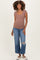 woman wearing a brown ribbed maternity top and distressed wide-leg jeans, showing off her baby bump