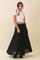 woman wearing a white ribbed crop top and a black flowy maxi skirt, styled with a printed scarf in her hair