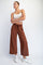 woman wearing a white cropped tank top and brown wide-leg pants with an elastic waistband, posing with arms crossed