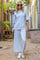 woman wearing a light blue two-piece lounge set with wide sleeves and wide-leg pants, paired with white sneakers and sunglasses