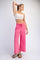 woman wearing a white crop top and pink wide-leg pants with a drawstring waist
