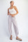 woman wearing a white cropped tank top and light pink ribbed jogger pants with pockets and slide sandals
