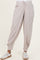 woman wearing light pink maternity joggers with side pockets and elastic cuffs, styled with white sneakers
