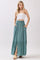 woman wearing a strapless white top and a teal maxi skirt with buttons and side pockets