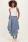 woman wearing a light blue denim maternity skirt with a button front and side pockets, styled with a sleeveless top