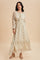 woman wearing a cream floral maxi dress with long sleeves and ruffled hem details