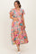 woman wearing a colorful floral print maternity dress and holding her baby bump