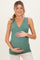 woman wearing a green maternity wrap tank top and holding her baby bump