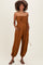 woman wearing a brown strapless maternity jumpsuit with pockets and a drawstring waist
