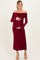 woman wearing a burgundy off-the-shoulder lace maternity dress with fitted waist and bell sleeves, holding her baby bump