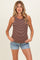 woman wearing a brown and white striped maternity tank top and denim shorts, standing with hands on her hips