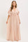 woman wearing a blush pink maxi dress with ruffled sleeves and a tie-front detail, standing barefoot