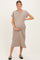 woman wearing a taupe maternity dress with short sleeves and a pocket, holding her baby bump