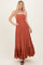 woman wearing a rust brown off-the-shoulder maxi dress with a smocked bodice and ruffled hem