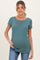 woman wearing a green short sleeve maternity top and holding her baby bump