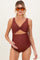 woman wearing a brown maternity swimsuit with a twist front design and holding her baby bump