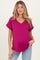 woman wearing a fuchsia short sleeve maternity top with a v-neck and pocket, showing her baby bump