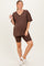 woman wearing a brown maternity v-neck oversized t-shirt and brown maternity bike shorts with a baby bump visible