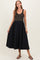 woman wearing a striped black and gold maternity dress with a flowing black skirt and sandals, showcasing her baby bump