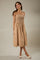 woman wearing a beige midi dress with a smocked bodice and thin straps, styled with white slip-on shoes