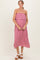 woman wearing a pink strapless maternity dress with a ruffled bodice and a flowing skirt, holding her baby bump